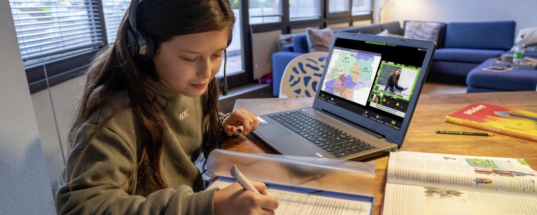 Das Bild zeigt ein Mädchen welches mit ihrem Laptop Hausaufgaben macht.