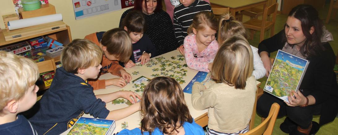 Sonja Schimmel und Jennifer Werner vom Regionalmanagement übergeben das Landkreis Puzzle Donau-Ries an die Kinder des Heilig-Kreuz Kindergartens in Donauwörth.