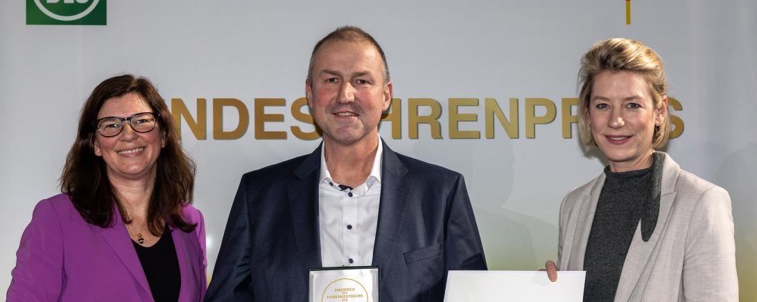 Die Parlamentarische Staatssekretärin Dr. Ophelia Nick (links) überreicht Urkunde und Medaille gemeinsam mit Freya von Czettritz, CEO der DLG-Holding, auf dem 13. Berliner Milchforum an Christian Schramm, Leiter Milcheinkauf bei der Zott SE & Co. KG.