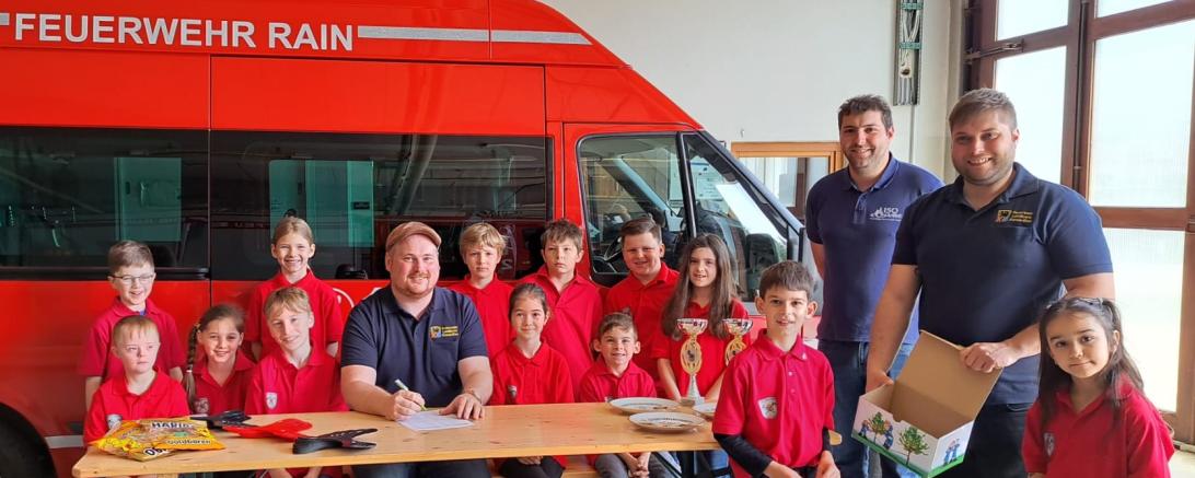 Die Kinder der Kinderfeuerwehr Rain am Lech beim Ziehen der Lose zusammen mit dem Organisationsteam Kreisjugendwart Markus Meyr (sitzend), Jugendwart der Freiwilligen Feuerwehr Rain am Lech Philipp Marb und Inspektionsjugendwart Stefan Eder.