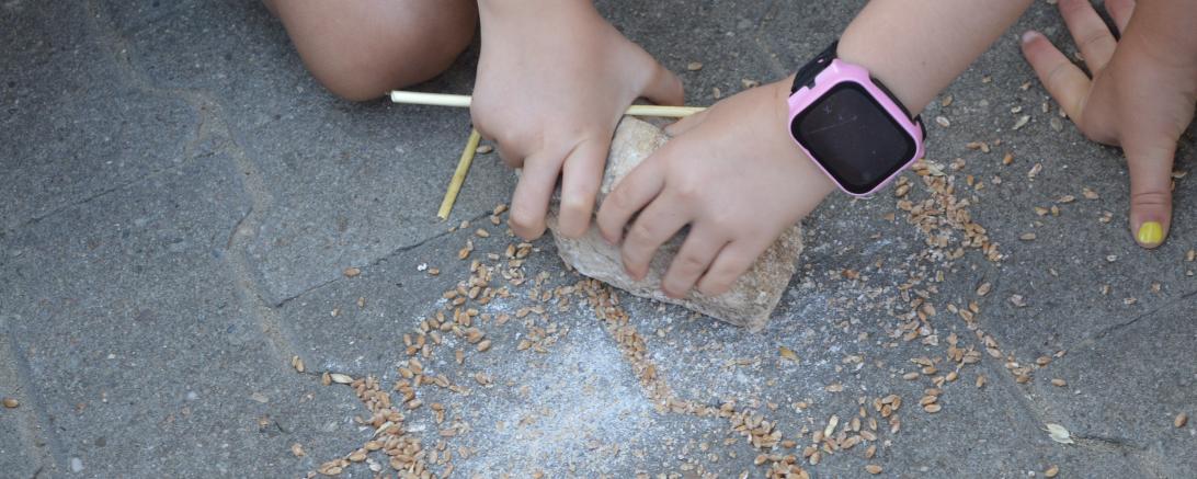 Kinder mahlen mit Stein Weizenkörner zu Mehl