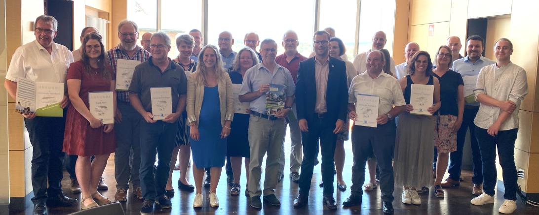 Das Interkommunale Netzwerk Flächensparen, bestehend aus dem Landkreis und seinen 44 Kommunen, bei der Übergabe der Urkunden des Netzwerkes und des Umweltpreises des Bezirks Schwaben mit dem Leiter der Stabsstelle Kreisentwicklung und Nachhaltigkeit Klemens Heininger und Konversionsmanagerin Barbara Wunder.