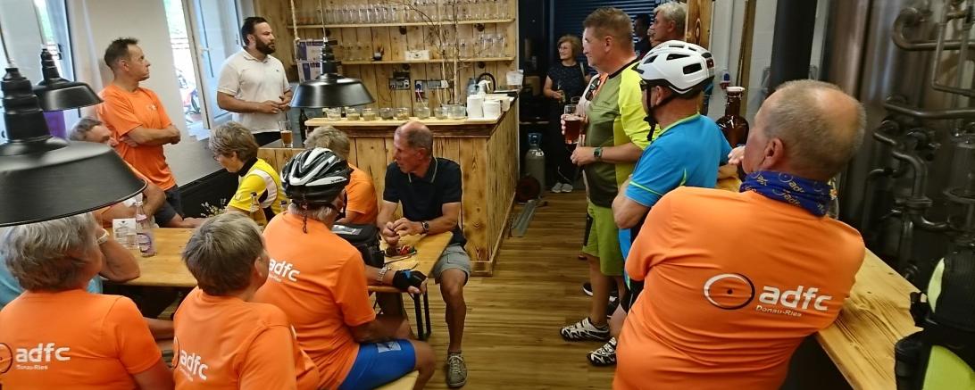 Das Donauwörther Brauhaus erstrahlte in orange. ADFC-Vorsitzender Steffen Reddel (links, stehend) und der Radverkehrsbeauftragte des Landkreises Donau-Ries, Alexander Wolfinger (3.v.r.) bedanken sich bei Bernhard Strauch vom Donauwörther Brauhaus (2.v.l., stehend) für die freundliche Aufnahme, das Freigetränk und die interessanten Informationen.