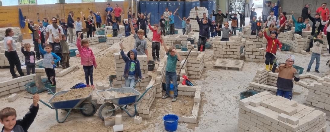 Das Bild zeigt viele Kinder beim Sommerferienprogramm der Bauinnung. 