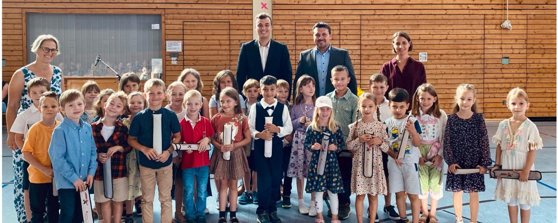 Unser Bild zeigt die Klasse 1a (oben) und die Klasse 1b (unten) mit der Direktorin Stefanie Fuß, den jeweiligen Klassenlehrer*innen, Susanne Ablaßmeier-Reiner (1a) und Robert Schmidt (1b), Bürgermeister Christoph Schmidt und den stellvertretenden Leiter der Geschäftsstelle Harburg, Sebastian Bitomsky.