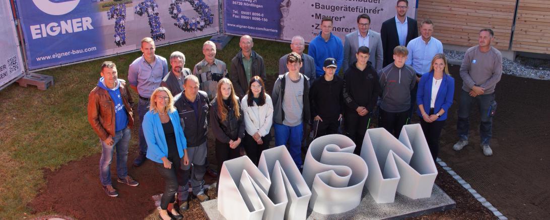 „Großer Bahnhof“ bei der Enthüllung des neuen Schullogs vor der Mittelschule in Nördlingen. Die sechs Jugendlichen, die am Projekt „Wir machen das“ teilgenommen haben zeigen sich mit den Ehrengästen und den Mitarbeitern der EIGNER Bauunternehmung
