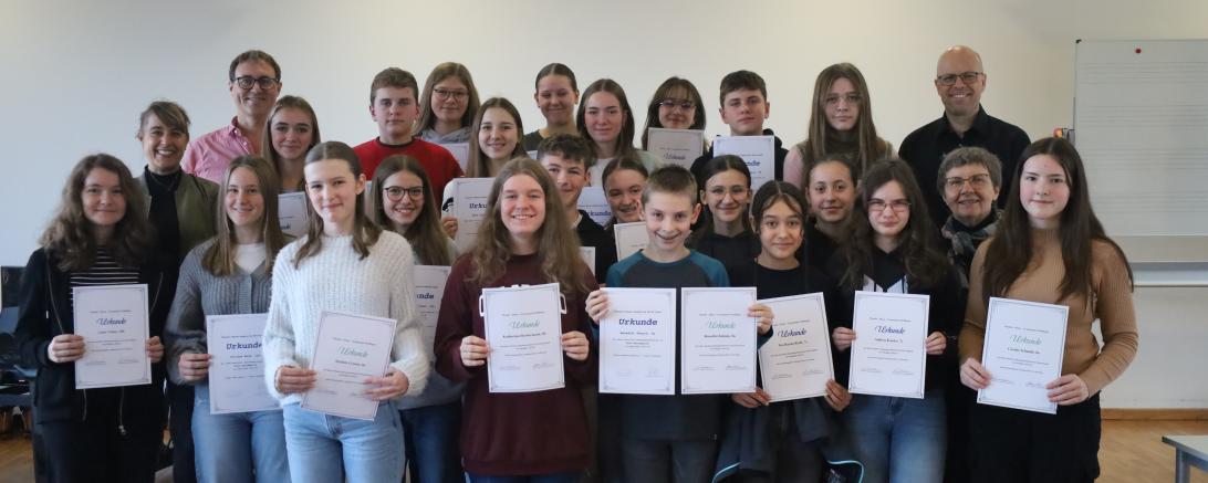 Stolz nahmen die Schülerinnen und Schüler die Urkunden für ihre Leistungen bei den Jahrgangsstufentests von Schulleiterin Dr. Renate Rachidi (vorne, 2. v. rechts) sowie den Fachbetreuern Sabrina Leidel (Deutsch, hinten, 1. v. links), Jürgen Christ (Mathematik, hinten, 2. v. links) und Mattias Lokietsch (Englisch, hinten, 1. von rechts) entgegen.