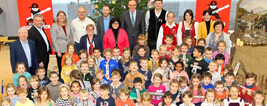 Hinter den Erstklässler:innen stehen (hintere Reihe von links) Schulamtsdirektor Michael Stocker, Stefan Reichherzer (Leiter der Sparkassenniederlassung Oettingen) Konrektorin Carola Haan, Armin Sailer (Elternbeirat und Förderverein „Move“) Bürgermeister und Schulverbandsvorsitzender Thomas Heydecker, Sparkassendirektor Johann Natzer, Achim Wunderle (Stadtkapelle), in der Reihe davor Michaela Wurm-Schaffer (Elternbeirat), Rektorin Ursula Hertle, Manuel Münderlein und Carina Stark (Blaskapelle Lehmingen) sow
