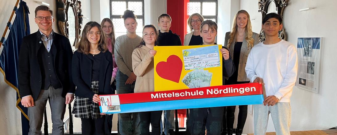 Schülerinnen und Schüler der Nördlinger Mittelschule übergeben gemeinsam mit ihrer Schulleiterin Marga Riedelsheimer 600 Euro für die „Nördlinger Hilfe in Not“ an Oberbürgermeister David Wittner (links) und Hauptverwaltungsleiterin Helena Ott (2. von rechts). 