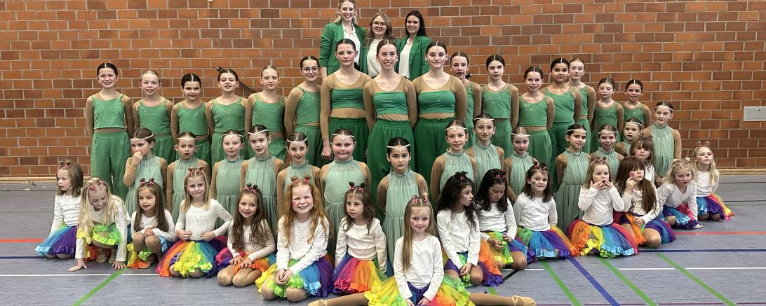 Das Bild zeigt die Mädchen der „Just Dance Minis“ in der vordersten Reihe, kniend in der mittleren Reihe die „Just Dance Kids“ und stehend in der hinteren Reihe die „Just Dance Teens“. Dahinter stehen die drei Trainerinnen, Meike Jörg, Lea Richter und Alina Schmidt.