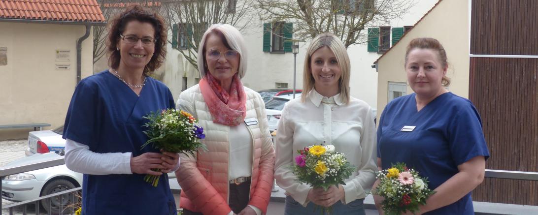 4 Personen, 3 Davon haben Blumen in der Hand