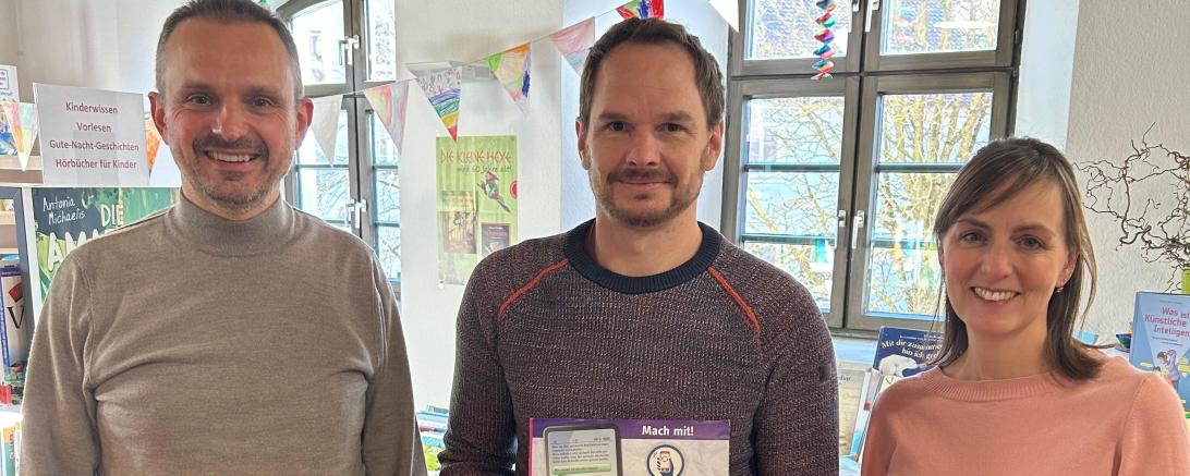 Drei Menschen, die Person in der Mitte hält eine Box.