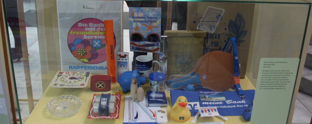 Hier sieht man verschiedene Werbemittel aus der Geschichte der Raiffeisen-Volksbank im Ries.
