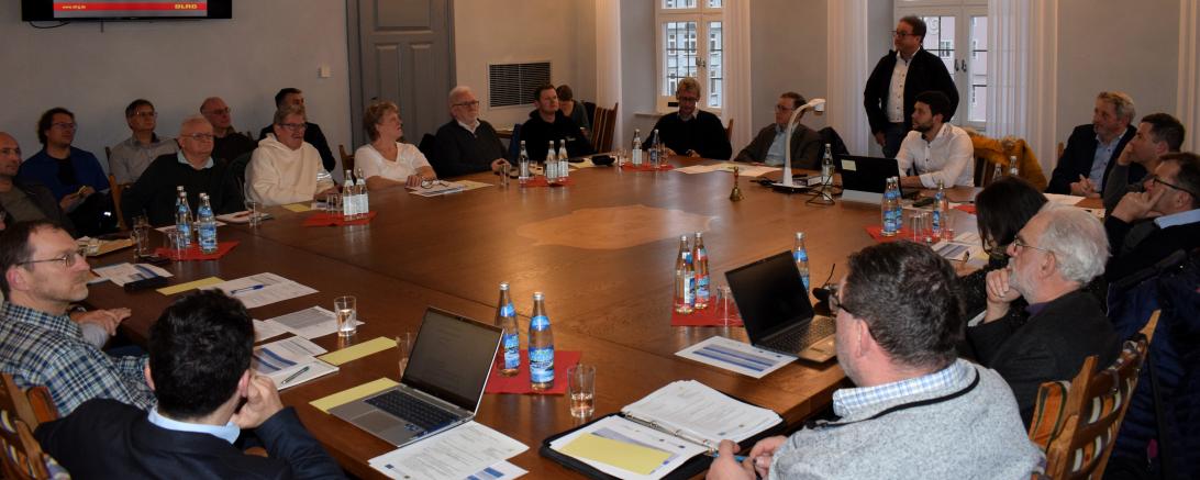 Die Mitglieder des Entscheidungsgremiums sitzen um einen Tisch