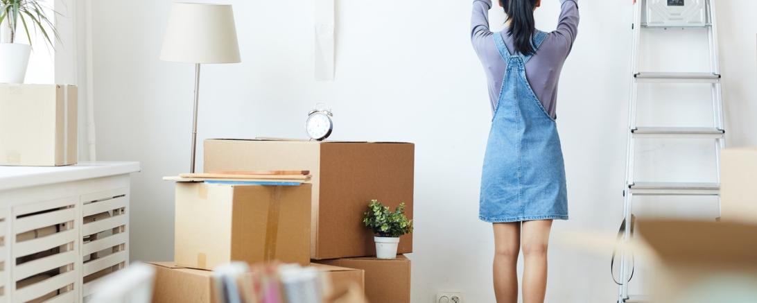 Frau hängt ein Bild auf 