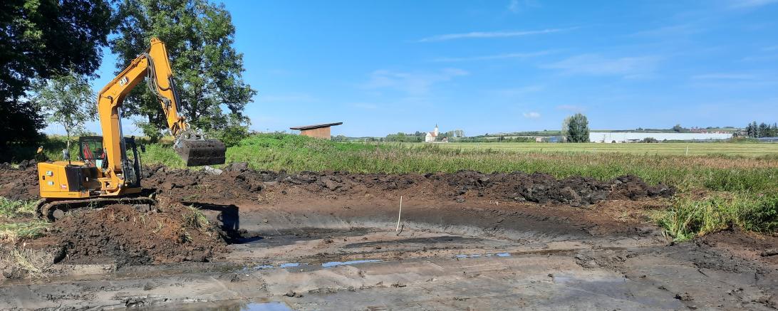 Hier sieht man einen Bagger, der einen Teich anlegt.