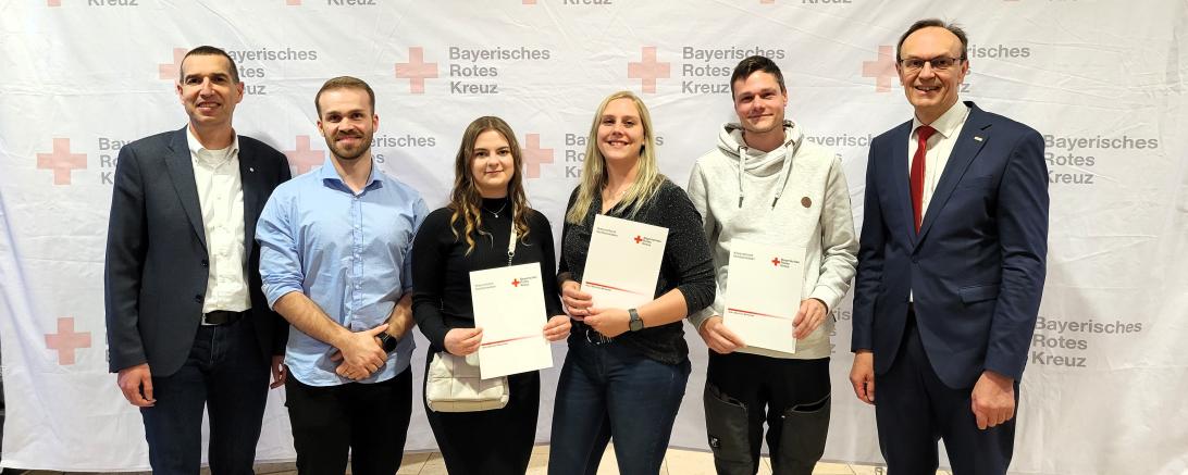 Hier sieht man die drei Absolventen mit Verantwortlichen des Bayerischen Roten Kreuz.