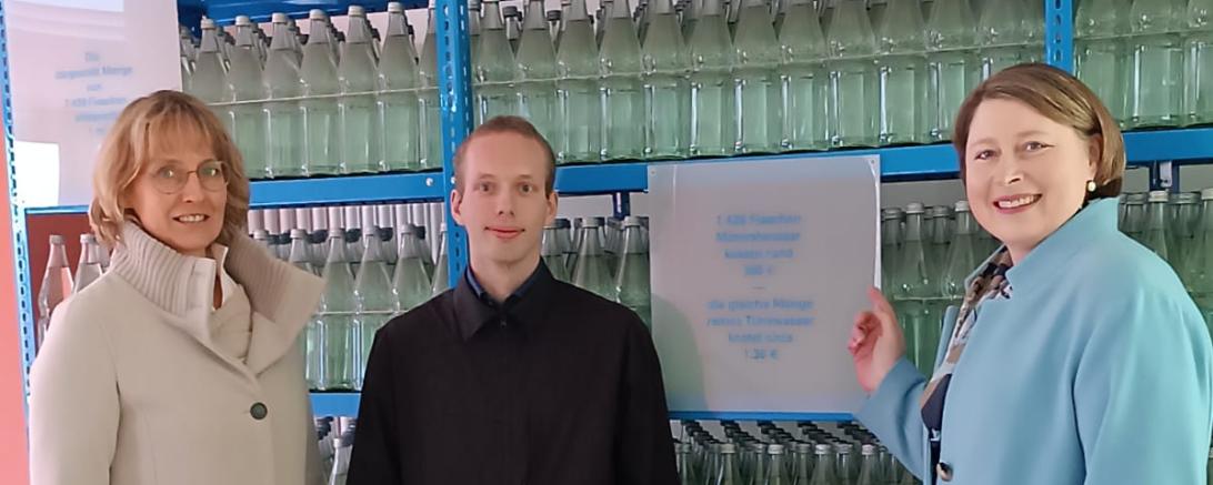 3 Menschen vor einem Regal mit Flaschen 