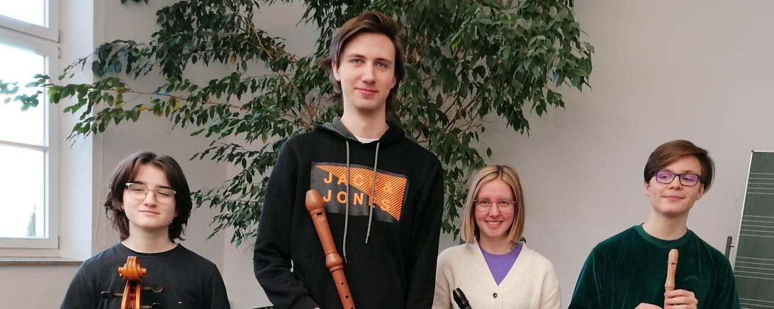 Drei Personen haben eine Blockflöte in der Hand, die Vierte Person hat ein Cello in der Hand und steht Links.