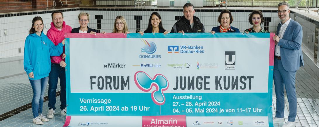 Menschen in einem Leeren Schwimmbecken die ein Banner halten