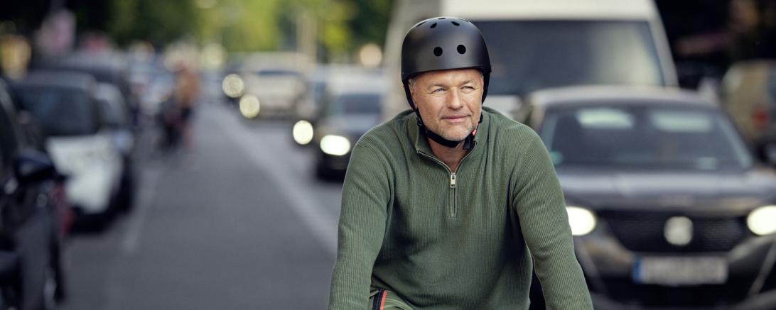 Hier sieht man einen Radfahrer im Berufsverkehr auf dem Weg zur Arbeit.