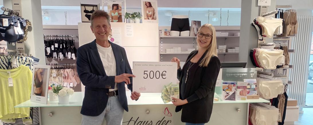 Zwei Menschen die einen Zettel heben auf dem 500 Euro Steht.