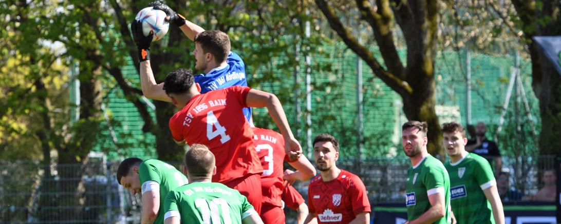 Fußballer in Roten und Grünen Trikots und ein Torwart in einem Blauen Trikot
