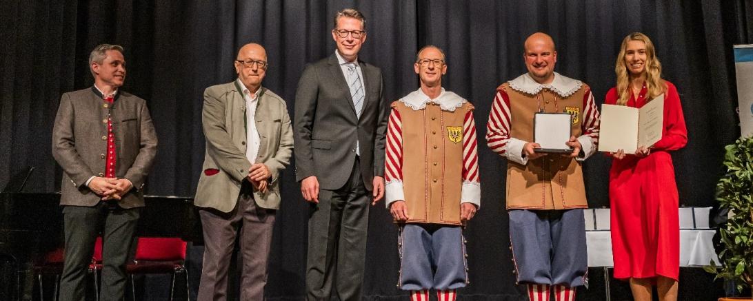 Staatsminister Markus Blume überreicht die Pro Musica-Plakette an die Knabenkapelle Nördlingen für ihren 100-jährigen Einsatz. Von links: Vizepräsident des Allgäu-Schwäbischen Musikbundes e. V. Patrick Scheel, Präsident des Bayerischen Musikrats e. V. Dr. Helmut Kaltenhauser, Bayerischer Staatsminister für Wissenschaft und Kunst Markus Blume, Leiter des Trommlerkorps Michael Fischer, Stadtkapellmeister Oliver Körner und Hauptverwaltungsleiterin Helena Ott.
