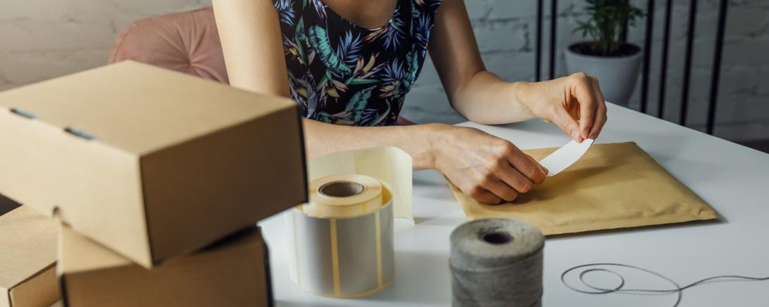 Das Bild zeigt eine Frau beim verschicken von Paketen. 