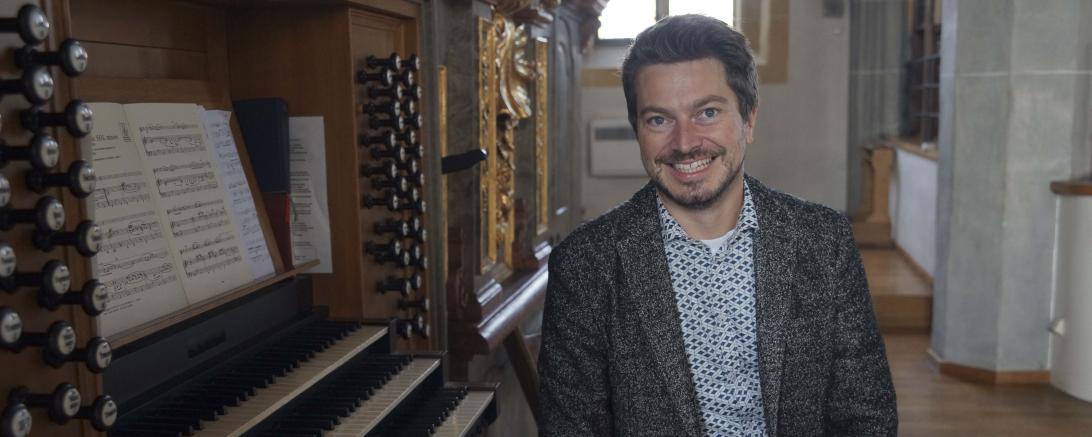 Hier sieht man André Gold vor einer Orgel.