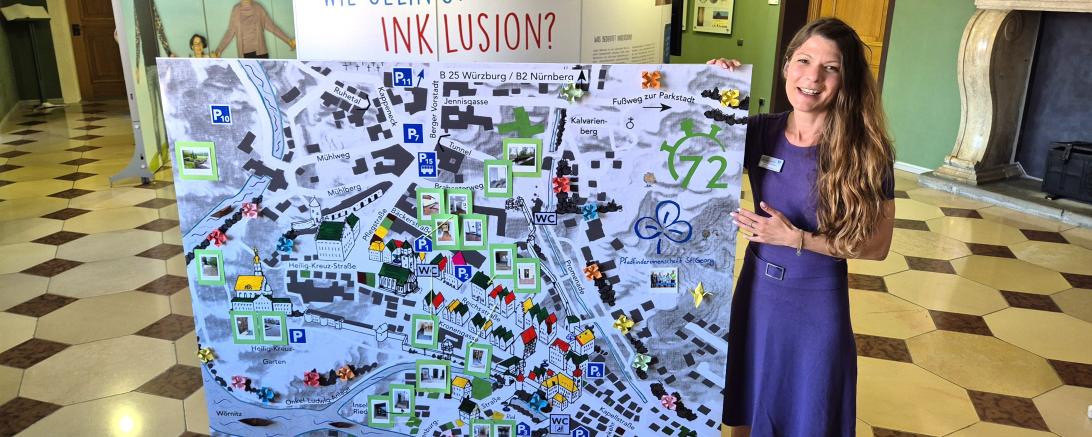 Sabrina Daniels-Wittmeier (Beauftragte für Menschen mit Behinderung bei der Stadt Donauwörth) mit dem Stadtplan der PSG Donauwörth vor der Wanderausstellung