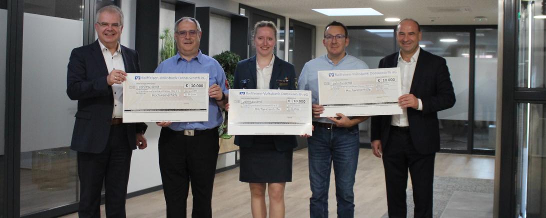 Bei der symbolischen Scheckübergabe v.l.n.r.: Michael Kruck (Sprecher des Vorstands), Heinz Mayr (Kreisfeuerwehrverband), Franziska Baur (THW), Branko Schäpers (Caritasverband) und Alexander Lehmann (Bankvorstand).