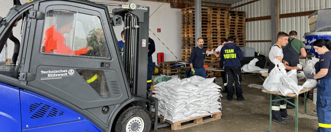 Ehrenamtliche Helfer*innen des THW Donauwörth befüllen Sandsäcke. 