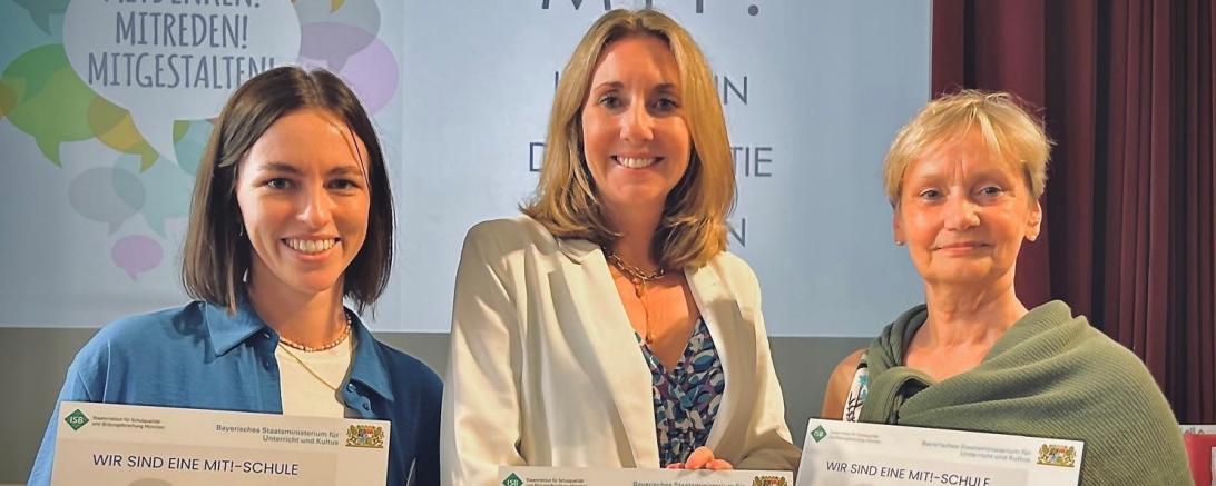 Auf dem Bild zu sehen (von links): Lehrerin Laura Mück, Kultusministerin Anna Stolz und Rektorin Margit Stimpfle.