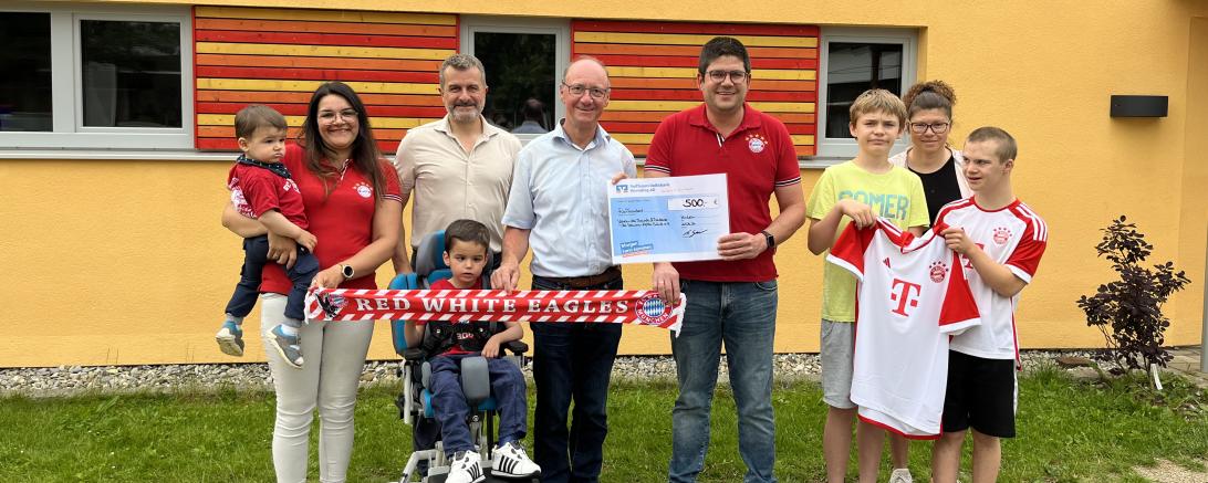 Yvonne Gail mit Sam Gail auf dem Arm, Ben Gail (sitzend vorne), Bereichsleitung Timm Albert, Vorstand des Fördervereins Erwin Seiler, 1. Vorstand des der Red-White-Eagles-Huisheim Michael Gail, Abordnung der HKS-Fußballer Dennis, Trainerin Simone Knaub und Elias.