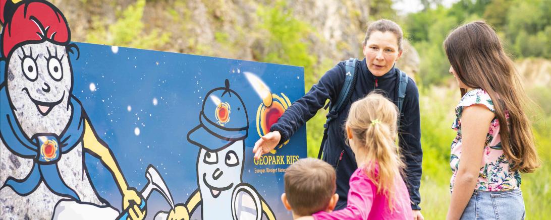 Das Bild zeigt die Geopark-Maskottchen Riesitchen und Suevitchen im Geotop Lindle.