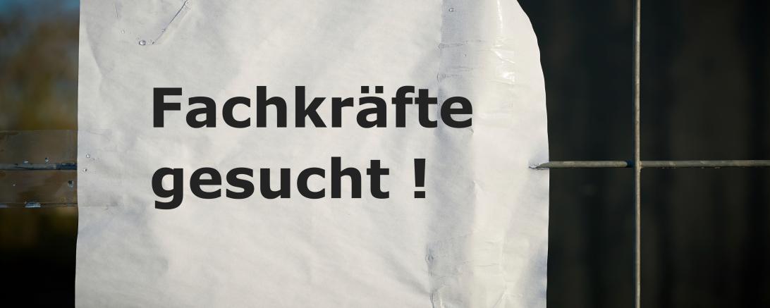 Das Bild zeigt ein Schild mit der Aufschrift Fachkräfte gesucht. 