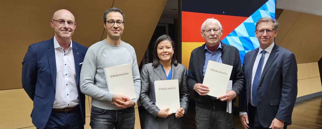 Drei neue Staatsbürger präsentieren ihre Urkunden, begleitet von Johann Stark, Fachbereichsleiter Personenstands- und Ausländerwesen, Staatsangehörigkeitsrecht und Landrat Stefan Rößle, die die Verleihung würdigten.