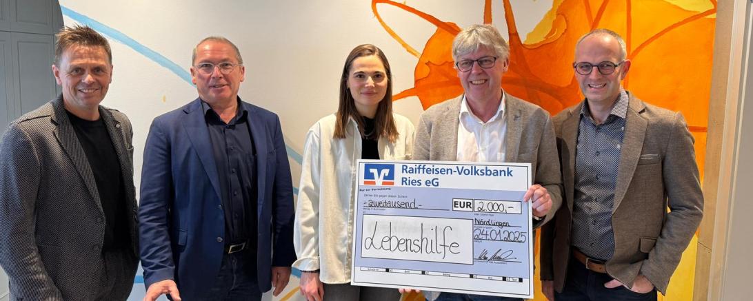 5 Menschen, zwei davon mit einem großen Geldscheck in der Hand