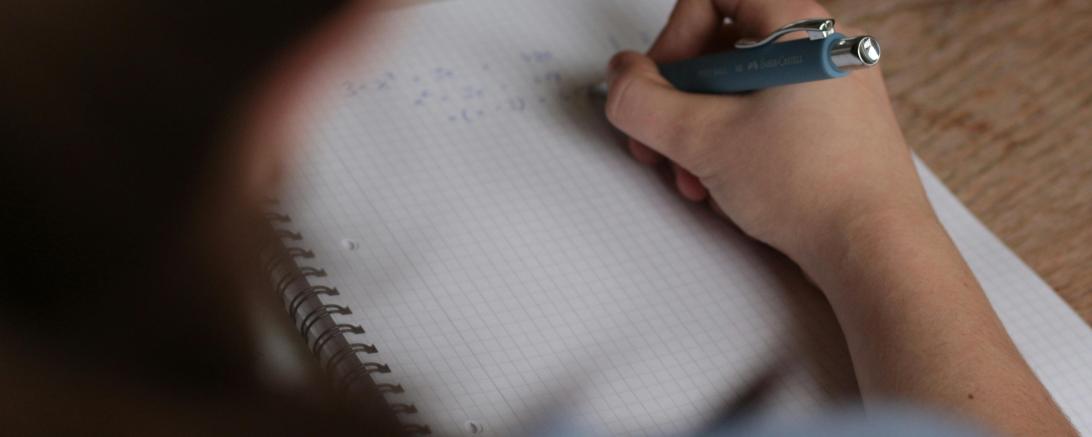 Eine Person schreibt auf ein Blatt Papier