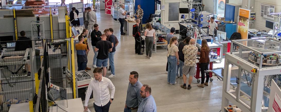 Besucher:innen informieren sich an den einzelnen Stationen in der Robotikhalle.
