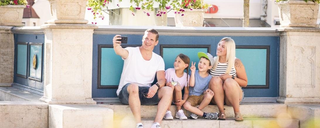Menschen sitzen vor dem Mangoldbrunnen in Wemding