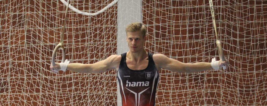 Sascha Wilhelm hier bei dem klassischem Kreuzhang an den  Ringen führt sein Team diszipliniert an.