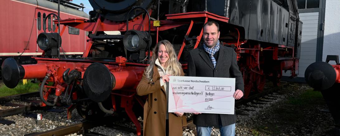 Barbara Wunder und Patrick Zeitlmann bei der Scheckübergabe vor historischer Kulisse im Bayerischen Eisenbahnmuseum Nördlingen.