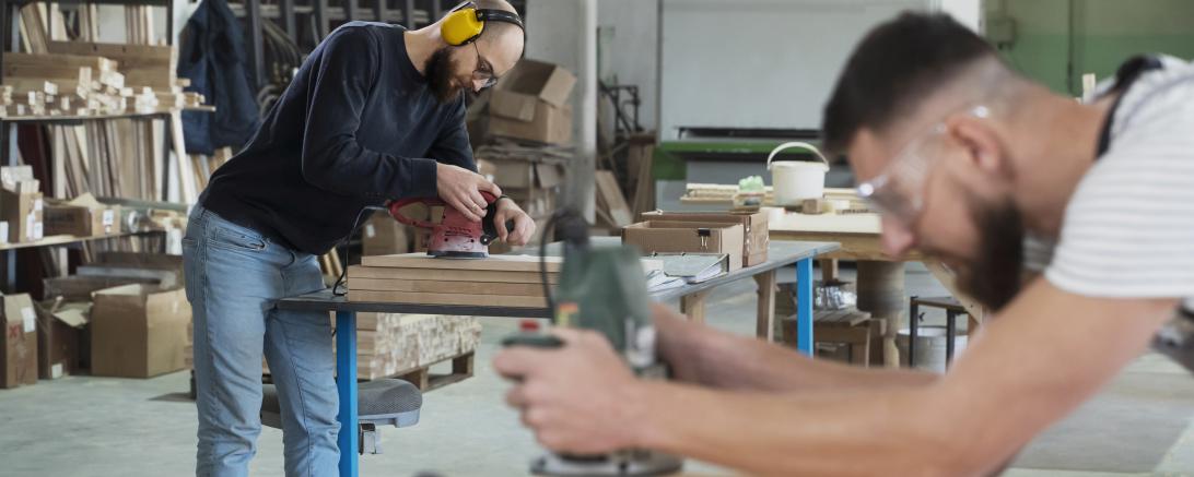 Zwei Männer arbeiten in einer Schreinerwerkstatt. 