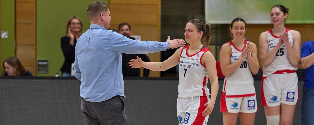 Nördlingens Coach Nico Kuusi (l.)  war es vorbehalten, seine Spielführerin Laura Schinkel (M.) mit bewegenden Worten zu verabschieden. Im Hintergrund applaudieren Sam Ashby (2.v.r.) und Natalie Kucowski. Auch der sportliche Leiter der Eigner Angels, Martin Fürleger, wurde von Kuusi im Namen der Mannschaft mit einer sehr persönlichen Ansprache und großem Applaus von allen Seiten verabschiedet.