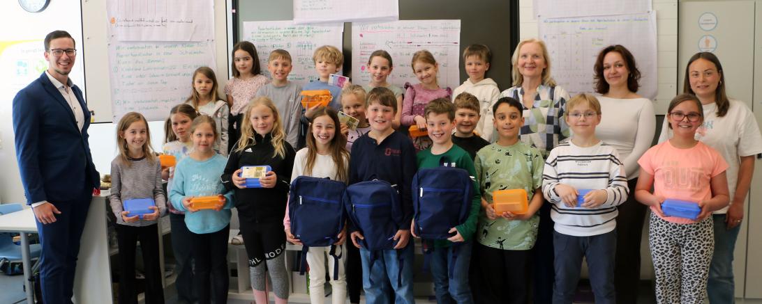 Das Bild zeigt die Sieger Mia, Ferdinand und Max (vorne mit Rucksäcken) mit ihren Klassenkameraden sowie Patrick Senft (links) und Sophie Dokter, Amelie Schmid und Gudrun Meier (hinten von rechts)
