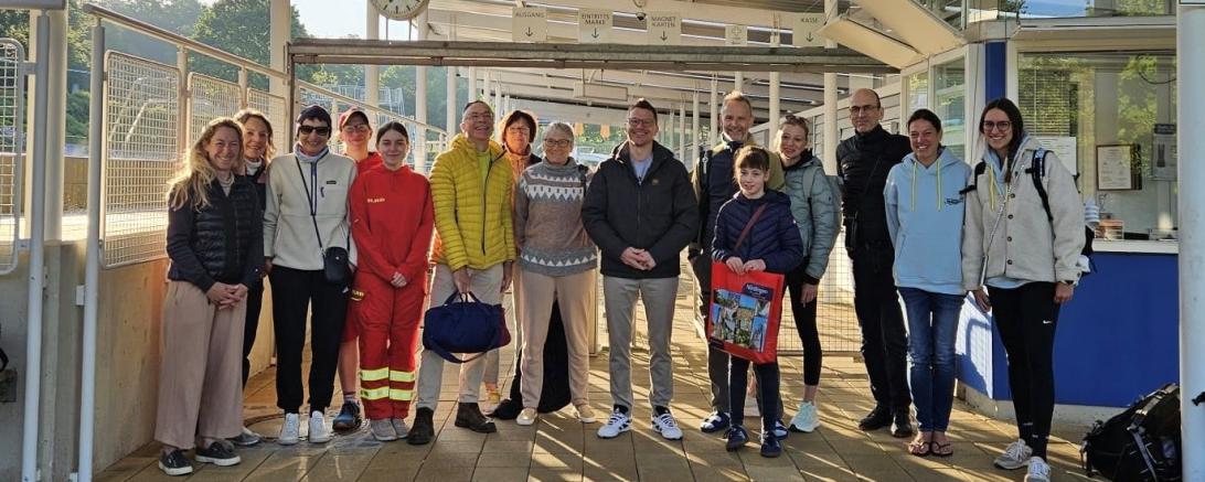 Gemeinsam mit Oberbürgermeister David Wittner (7. v. r.) eröffneten Stadträtin Barbara Wunder (1. v. l.) und Stadtrat Wolfgang Goschenhofer (7. v. l.) die Freibadsaison 2026. Begrüßt wurden dabei Ida Dietz (5. v. r.) als erste Besucherin des Jahres sowie zahlreiche weitere Badegäste.