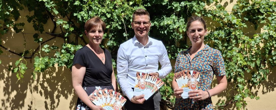 Der Countdown für die Sommerferien läuft: Mit  dem neuen Flyer startet das Ferienprogramm 2026 bald in die  Anmeldephase (v. l.: Simone Leidel, Oberbürgermeister David  Wittner, Jugendsozialarbeiterin Nina Thorwart).