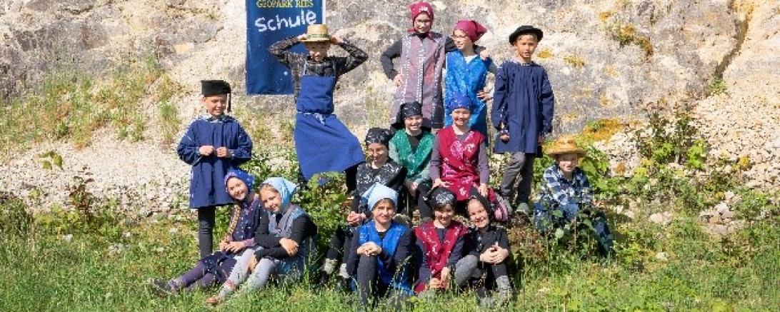 Schülerinnen und Schüler der Grundschule Mönchsdeggingen präsentieren Kittelschurz, Blauhemd und Arbeitskleidung in den Geotopen Kühstein.